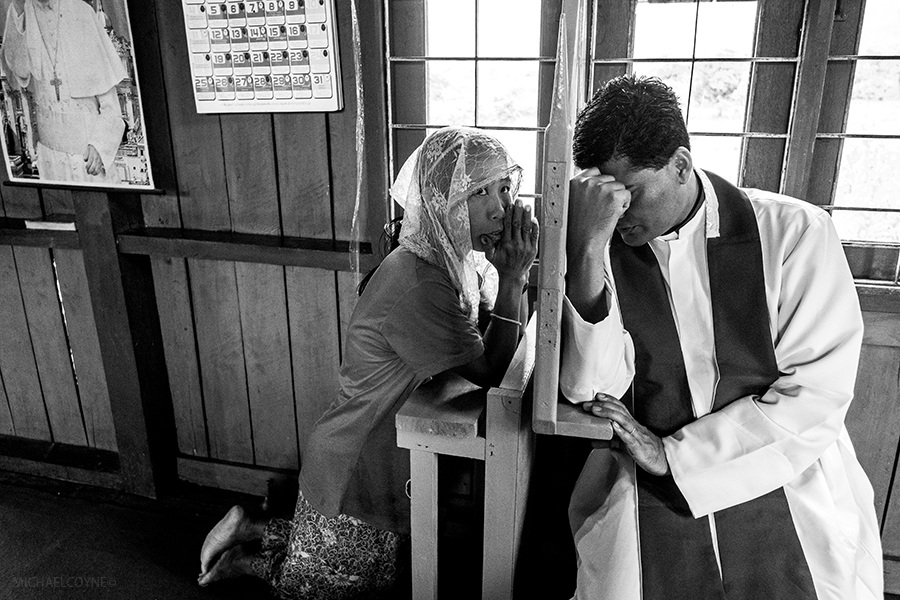 A Catholic priest hears the confession of an ethnic Wa woman. Lahio, Shan, Myanmar